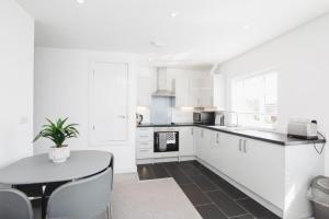 a kitchen with white cabinets and a table with a potted plant at NEW 2BD Pontact Flat in the Heart of Didcot in Didcot