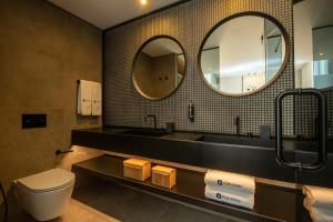 a bathroom with a sink and a toilet and mirrors at Ferraria XVI FLH Hotels Lisboa in Lisbon