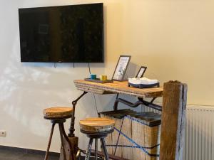 a table with two stools and a television on a wall at Berthe Artist House in La-Roche-en-Ardenne