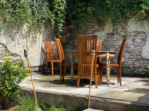 a group of wooden chairs and a table in front of a stone wall at Berthe Artist House in La-Roche-en-Ardenne