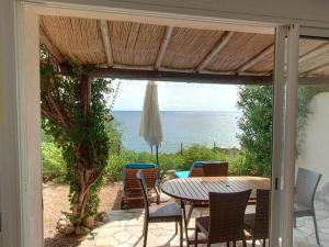 un patio con mesa, sillas y el océano en La Côte Bleue, en Sainte-Lucie de Porto-Vecchio