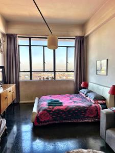 um quarto com uma cama e uma grande janela em Modern city apartment in Johannesburg - Maboneng em Joanesburgo