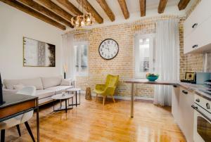 a living room with a couch and a clock on a brick wall at Curcumelli Luxury Suites - Κorkira in Corfu