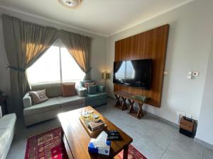 ein Wohnzimmer mit einem Sofa und einem TV in der Unterkunft الشروق شقه فندقيه vip البيت بيتك in King Abdullah Economic City