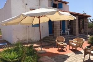 una sombrilla blanca grande y algunas sillas y una mesa en Villa panoramica nel golfo Asinara en Sorso