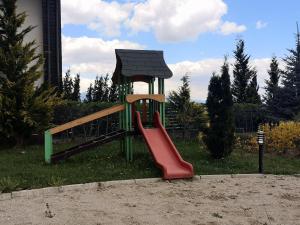 a playground with a red slide in the grass at Студио за трима, басейн, Aspen Golf Resort, Банско, Разлог in Razlog