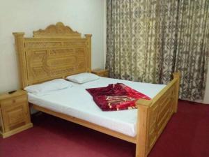 - une chambre avec un lit en bois et une couverture rouge dans l'établissement Hotel Pine View & Restaurant, à Bālākot