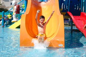 a boy is in the pool with a surfboard at Jupiter Albufeira Hotel - Family & Fun in Albufeira