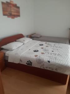 Una cama con un edredón blanco con flores. en Apartmani Danica en Pirovac