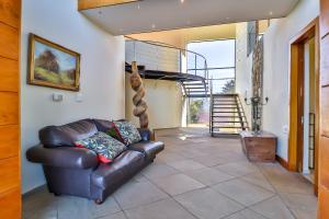 a living room with a leather couch and a spiral staircase at Lighthouse in Brenton-on-Sea