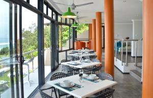 a restaurant with tables and chairs and large windows at Greenfire Umdloti Bed & Breakfast in Umdloti