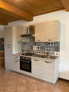 La cuisine est équipée de placards en bois et d'un four avec plaques de cuisson. dans l'établissement casa vacanze B&B ilciliegio, à Bovegno