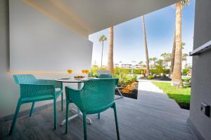 a patio with a table and chairs and palm trees at Relaxia Los Girasoles Bungalows in Playa del Ingles
