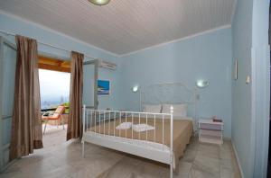 a bedroom with a white bed and a balcony at Studio Tasos in Gaios