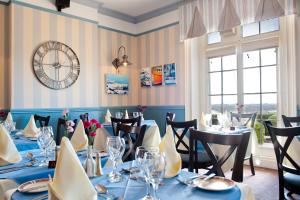 a restaurant with blue tables and chairs and a clock at Pontac House Hotel in St. Clements