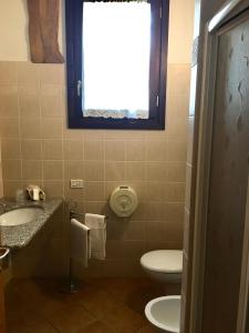 baño con aseo y lavabo y ventana en albergo panoramico, en Lenna