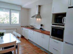 eine Küche mit weißen Schränken und einem Herd mit Backofen in der Unterkunft HOLIDAY HOMES by del abuelo VEGADEO in Vegadeo