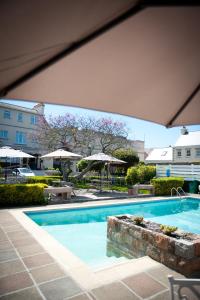 a large swimming pool with tables and umbrellas at Pontac House Hotel in St Clements