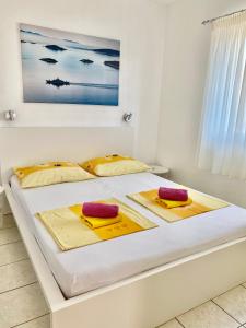 a bedroom with a white bed with yellow and red pillows at Colonia Apartments in Orebić