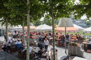 a crowd of people sitting at tables in an outdoor restaurant at Hotel New York by WestCord in Rotterdam
