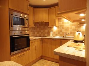 a kitchen with wooden cabinets and a stove top oven at Central Apartment Kelso in Kelso