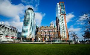 two tall buildings in a city with a grass field at Hotel New York by WestCord in Rotterdam