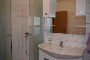 a bathroom with a sink and a shower with a mirror at Apartman Julka in Sukošan