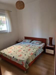 a bedroom with a bed with a comforter and a window at Apartman Julka in Sukošan