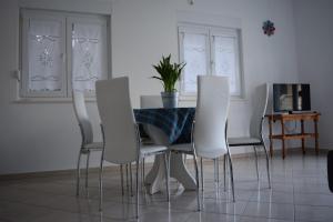 a dining room with a table and white chairs at Apartman Julka in Sukošan