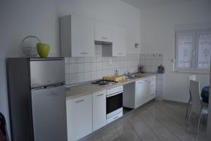 a kitchen with white cabinets and a black refrigerator at Apartman Julka in Sukošan