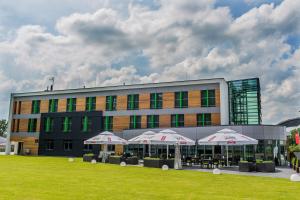 ein Gebäude mit Tischen und Sonnenschirmen davor in der Unterkunft Hotel Astone Conference & Spa in Lubin
