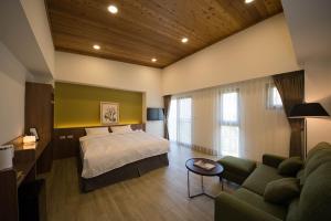 ein Schlafzimmer mit einem Bett, einem Sofa und einem Tisch in der Unterkunft 南窩綠丘-綠丘行旅 in Tongxiao
