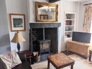 a living room with a fireplace and a television at Rose Cottage in Ulverston