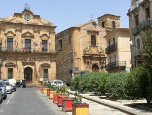 un antiguo edificio con coches aparcados en una calle en Al Campanile, en Piazza Armerina