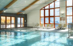 a swimming pool with chairs in a room with windows at Résidence Labellemontagne Rochebrune LE VALLON**** in Orcières