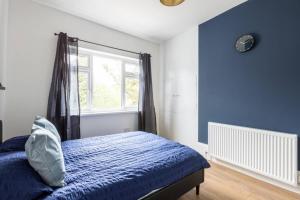 a bedroom with a bed with blue walls and a window at The Cumbria House 5 bedroom House Stay in London