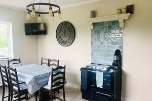 ein Esszimmer mit einem Tisch und einer Uhr an der Wand in der Unterkunft Eden Cottage in Lisburn