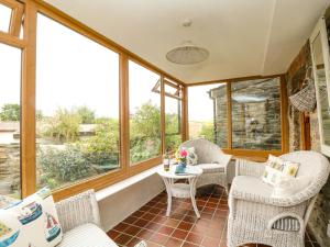 eine abgeschirmte Veranda mit Stühlen und einem Tisch in der Unterkunft Uphill Cottage in Saint Ervan