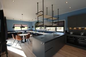 cocina con paredes azules y comedor en Hofparken Wiltershaar - groepsaccommodatie met privé wellness, en Kotten