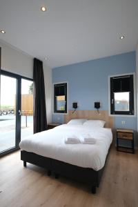 a large bedroom with a large white bed and windows at Hofparken Wiltershaar - groepsaccommodatie met privé wellness in Kotten