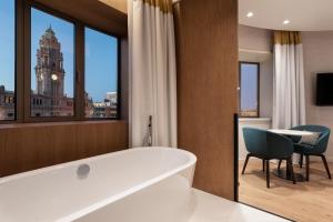 a bath room with a large tub and a large window at Eurostars Aliados in Porto
