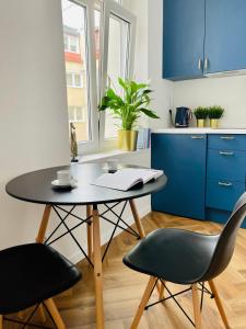 uma mesa e cadeiras numa cozinha com armários azuis em 20 m2 SOPOT centrum parking za darmo em Sopot