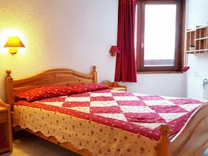 een slaapkamer met een quilt op een bed met een raam bij Appartement La Tania, 3 pièces, 7 personnes - FR-1-513-38 in La Tania