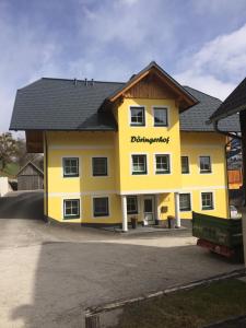 ein großes gelbes Gebäude mit schwarzem Dach in der Unterkunft Appartement Döringerhof in Aich