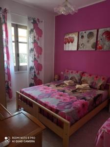 1 dormitorio con cama y pared púrpura en Da Andrea & Viola, en Terralba
