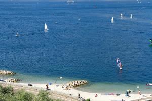 a beach with people and sailboats in the water at VistaLago Torbole in Nago-Torbole