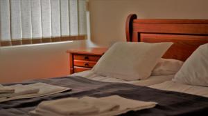 a bed with white sheets and pillows and a wooden headboard at Pirin Place Bansko in Bansko