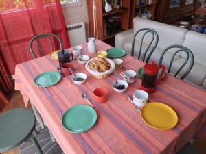stół z zielonymi talerzami i kosz z jedzeniem w obiekcie Domi et les chats w mieście Barbezières