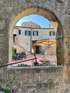 an arch in a stone wall with a table and umbrella at Hotel Della Fortezza in Sorano