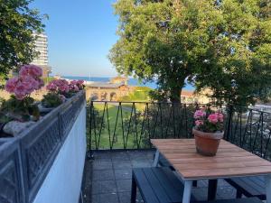 einen Tisch und eine Bank auf einem Balkon mit Blumen in der Unterkunft Warwick House - Stunning house with terrace and sea views, sleeps 11 in Worthing